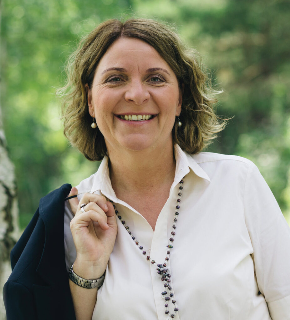 Cornelia Stieler mit Blazer locker über den Zeigefinger gehakt.